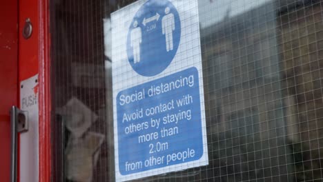 Handheld-Close-Up-of-Social-Distancing-Sign-In-Shop-Window