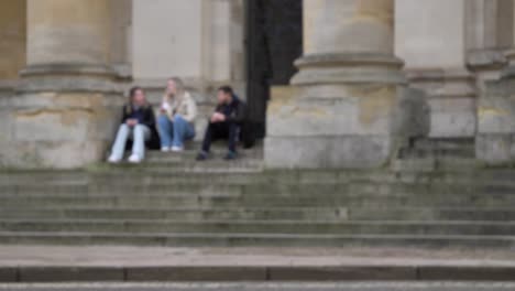 Defocused-Wide-Shot-of-People-Sitting-On-Steps-of-Clarendon-Building-as-Pedestrians-Pass
