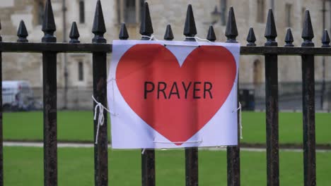 Handheld-Close-Up-Shot-of-A4-Prayer-Sign-Tied-to-Railing