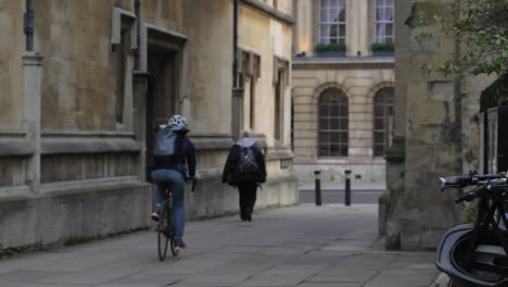 Handheld-Wide-Shot-of-Cyclist-and-Pedestrian-In-On-Catte-Street-In-Oxford