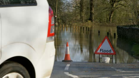 Long-Shot-of-Car-Driving-Past-Road-Closed-and-Flood-Signs-In-Front-on-Flooded-Road