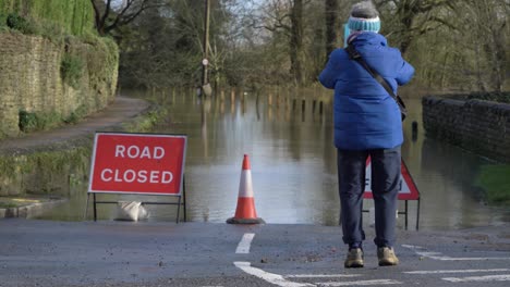 Long-Shot-of-Pedestrian-Photographing-Flooded-Road-