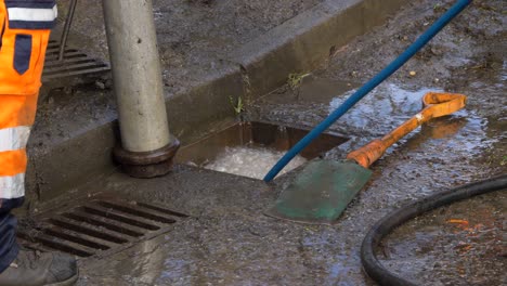Handheld-Nahaufnahme-Von-Sprudelndem-Wasser,-Während-Entwässerungsarbeiter-Versuchen,-Den-Abfluss-Zu-Entsperren