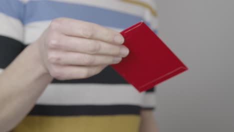 Close-Up-Shot-of-Hand-Giving-Chinese-New-Year-Red-Envelope-to-Person-