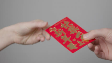 Close-Up-Shot-of-One-Hand-Taking-a-Red-Envelope-from-Another-On-Chinese-New-Year