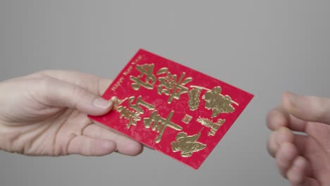 Close-Up-Shot-of-One-Hand-Taking-a-Red-Packet-from-Another-On-Chinese-New-Year