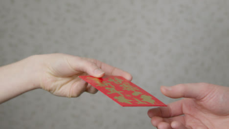 Close-Up-Shot-of-One-Hand-Taking-Red-Envelope-from-Another-On-Chinese-New-Year
