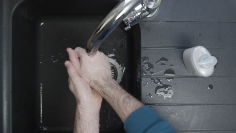 Top-Down-Shot-of-Male-Hands-Washing-with-Soap-Under-Running-Tap