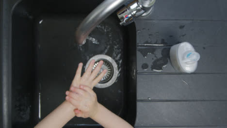 Top-Down-Shot-of-Young-Childs-Hands-Washing-Under-Tao-Before-Turning-It-Off