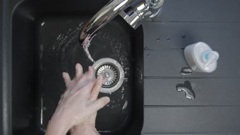 Top-Down-Shot-of-Female-Hands-Rinsing-Soap-from-Hands-Under-Running-Tap