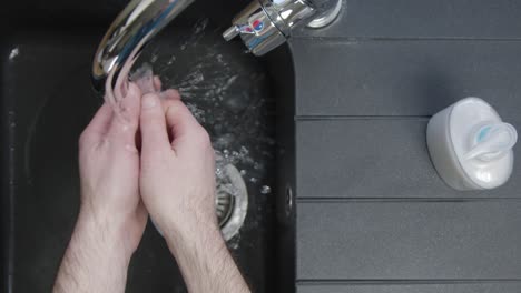 Top-Down-Shot-of-Male-Hands-Turning-On-Tap-and-Washing-Hands