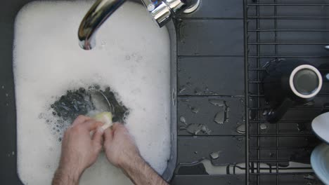 Top-Down-Shot-of-Male-Hands-Washing-Spoons-In-Sink-of-Soapy-Water