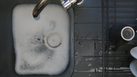 Top-Down-Shot-of-Soapy-Water-Running-Down-Sink-Plug-Hole-Leaving-Bubbles-Behind