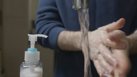 Close-Up-Shot-of-Male-Hands-Washing-Under-a-Running-Kitchen-Tap-with-Soap