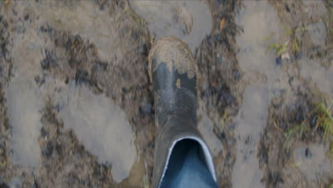 POV-Shot-Looking-Down-at-Boots-Walking-On-Wet-Muddy-Footpath
