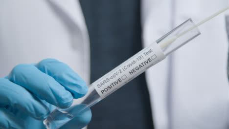 Close-Up-Shot-of-COVID-Test-Tube-as-médico-Professional-Places-Swab-In-It