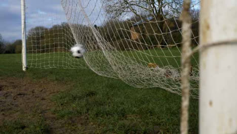 Medium-Shot-of-Soccer-Ball-Rolling-into-Goal-Net-Behind-Foreground-Post