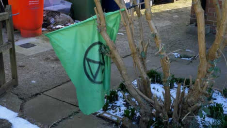 Pedestal-Shot-Rising-Up-Over-Wall-to-Reveal-Extinction-Rebellion-Flag-In-Tree