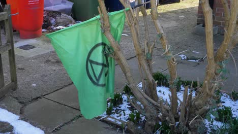 Pedestal-Shot-Rising-Up-Over-Wall-to-Reveal-Extinction-Rebellion-Flag-In-Tree