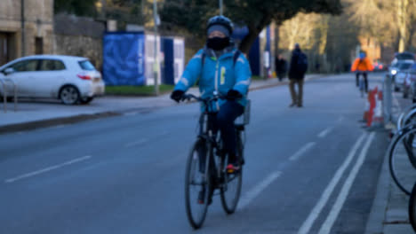 Defocused-Wide-Shot-of-Cyclist-Riding-Past-