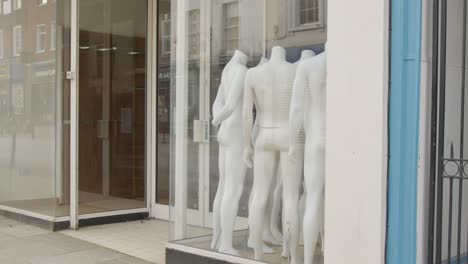 Tracking-Shot-Pulling-Away-from-Shop-Window-Full-of-Disused-Mannequins-