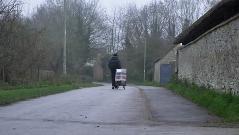 Wide-Shot-of-Person-Pulling-Sack-Truck-Down-Rural-Town-Footpath