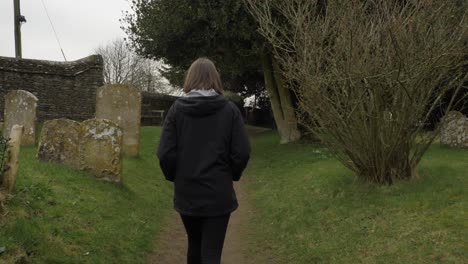 Tracking-Shot-Following-Young-Woman-Walking-Along-Graveyard-Footpath