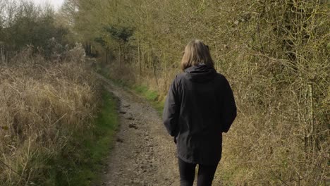 Tracking-Shot-Following-Young-Woman-Walking-Down-Rural-Footpath