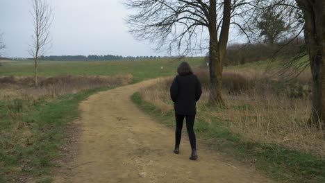 Tracking-Shot-Following-Young-Woman-Walking-Along-Countryside-Footpath