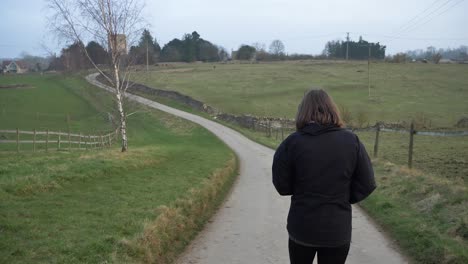 Tracking-Shot-Following-Woman-Walking-Down-a-Countryside-Road-