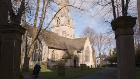 Wide-Shot-of-Elderly-Person-Pushing-Buggy-Past-Church