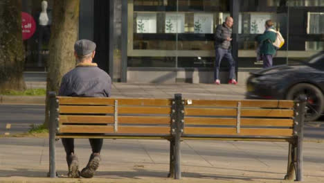 Long-Shot-of-Elderly-Person-Sitting-On-Street-Bench