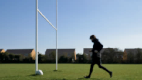 Defocused-Wide-Shot-of-Rugby-Player-Picking-Ball-and-Tee-Up-from-Next-to-Post