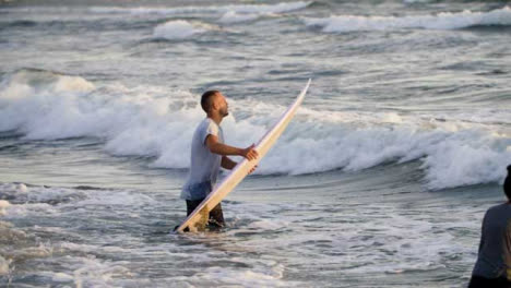Handheld-Long-Shot-Tracking-Surfer-Walking-Out-into-Ocean-