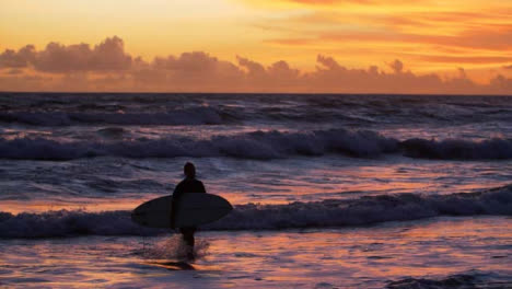 Handheld-Weitwinkel-Tracking-Surfer,-Der-Bei-Sonnenuntergang-Aus-Dem-Wasser-Geht