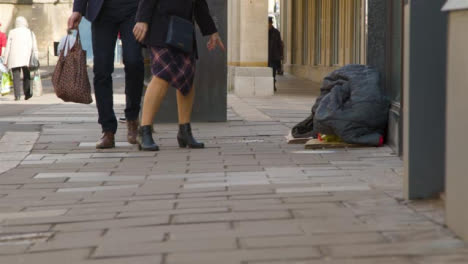 Wide-Shot-of-Pedestrians-Walking-Past-Homeless-Persons-Belongings-On-Street