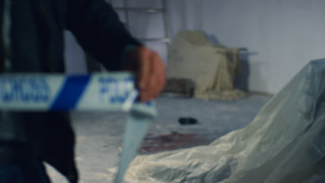Close-Up-Shot-of-Detective-Pulling-Police-Tape-In-Disused-Warehouse