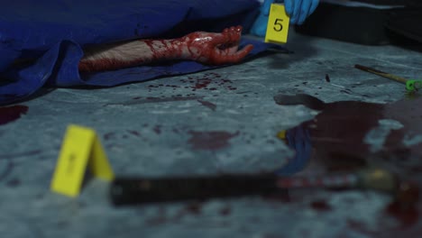 Sliding-Close-Up-Shot-of-Evidence-Tag-Being-Placed-Next-to-Bloody-Hand-at-Crime-Scene