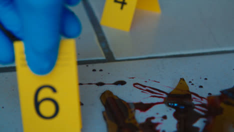 Sliding-Extreme-Close-Up-Shot-of-Evidence-Tags-On-Floor-Next-to-a-Bloody-Broken-Bottle