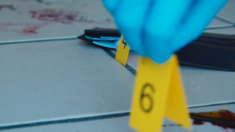 Sliding-Close-Up-Shot-of-Evidence-Tags-On-Floor-Next-to-a-Bloody-Broken-Bottle