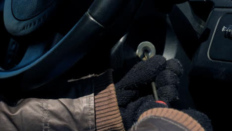 Sliding-Close-Up-Shot-of-Thief-Attempting-to-Access-Car-Ignition-with-Screwdriver