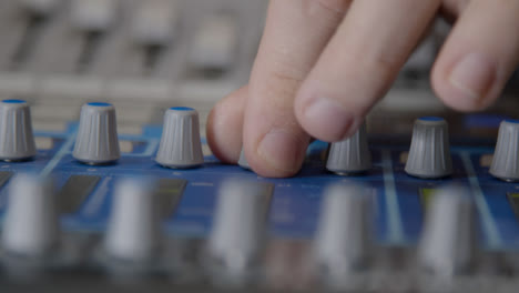 Close-Up-Shot-of-Sound-Mixers-Hand-Adjusting-Knobs-On-Sound-Board