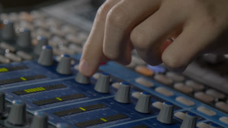Close-Up-Shot-of-Sound-Mixers-Hand-Pressing-Button-and-Adjusting-Knobs-On-Sound-Board