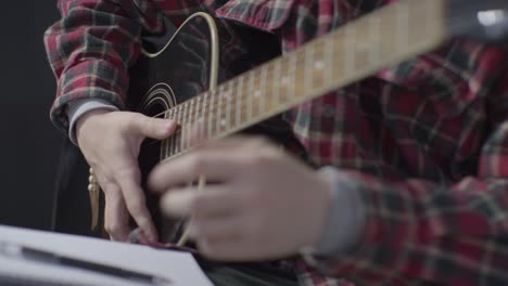 Medium-Shot-of-Musician-Holding-Acoustic-Guitar-and-Writing-