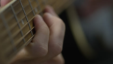 Sliding-Extreme-Close-Up-Shot-of-Musicians-Hands-On-Acoustic-Guitar-Fret-Board