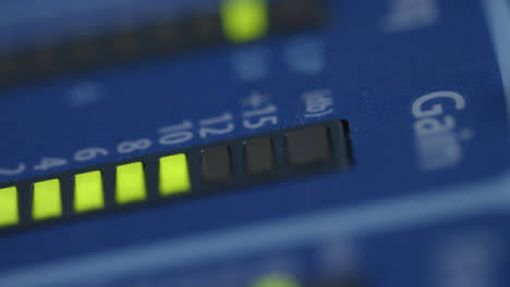 Tracking-Extreme-Close-Up-Shot-of-Gain-Lights-On-Audio-Mixing-Board