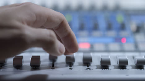 Tracking-Close-Up-Shot-of-Audio-Mixers-Hand-Adjusting-Faders-On-Audio-Mixing-Board