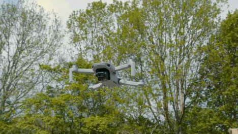 Low-Angle-Shot-Orbiting-DJI-Mini-2-Drone-Hovering-In-Air