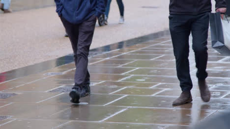 Medium-Shot-of-Pedestrians-Walking-On-Wet-Pavement-