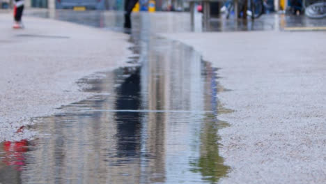 Close-Up-Shot-of-Rain-Drops-Falling-In-Puddle-In-City